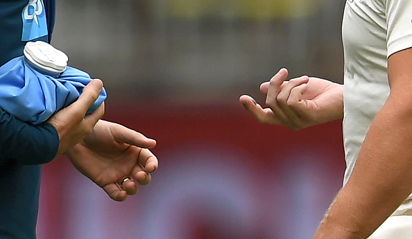 Physio looks at the injured finger of Aaron Finch | Getty